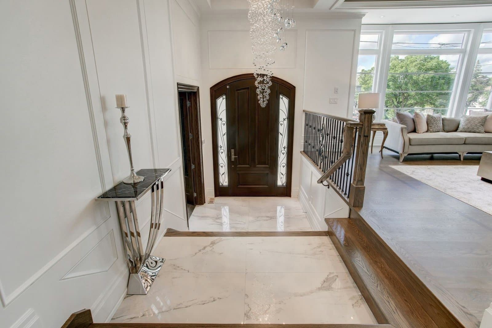 Arched stained wood entrance door with leaded glass sidelights, seen from the foyer