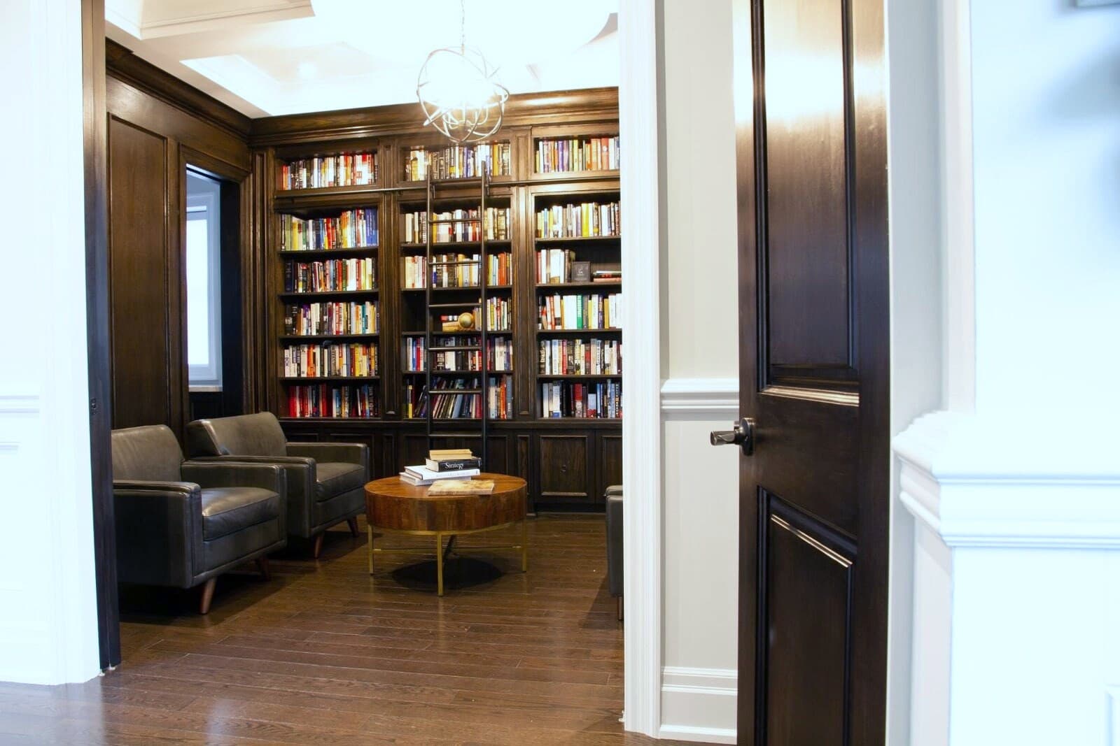 Walnut panelled library seen through an open door with dark stained casing