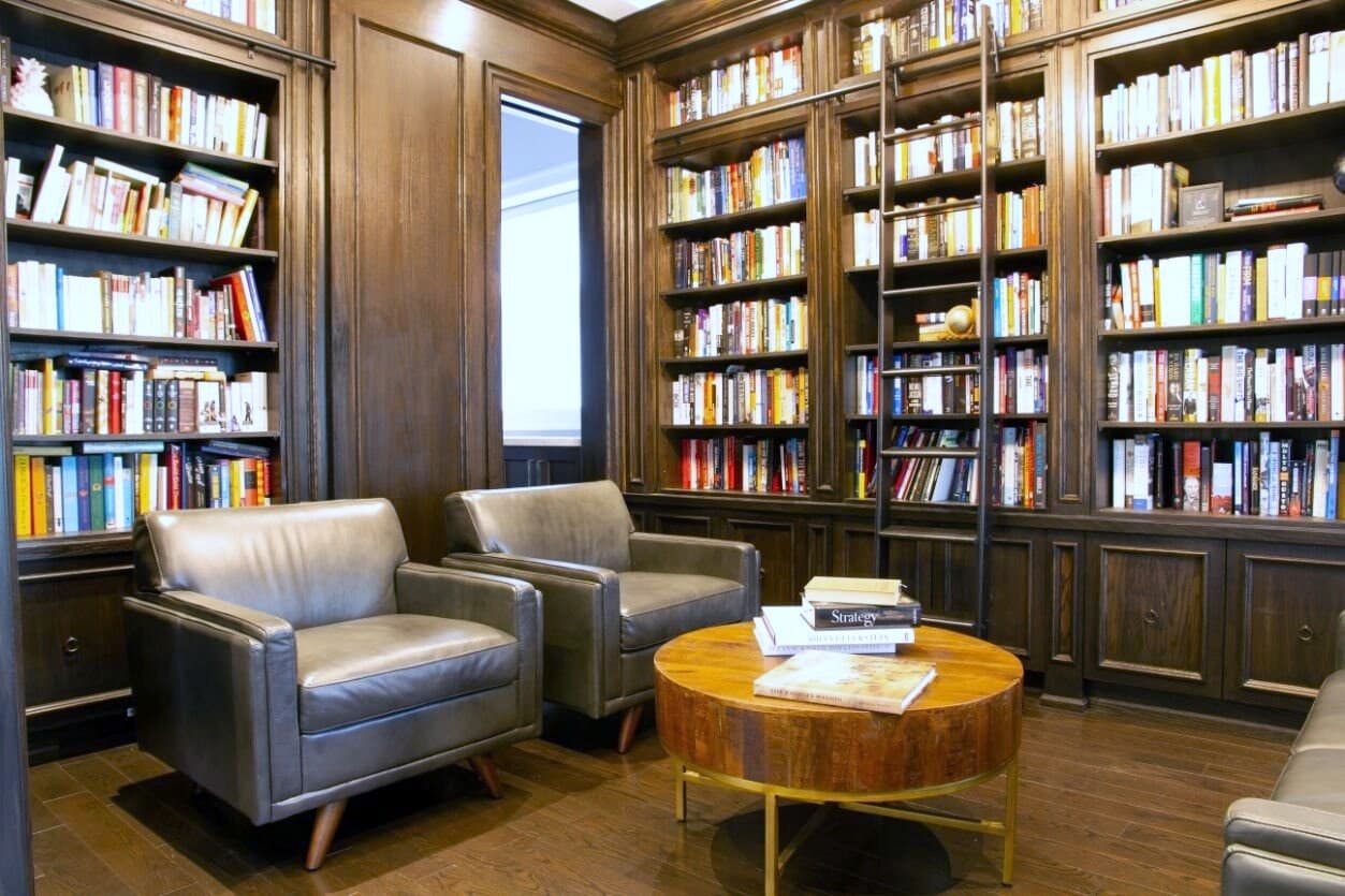 Walnut panelled library with a rolling ladder and full height bookshelves