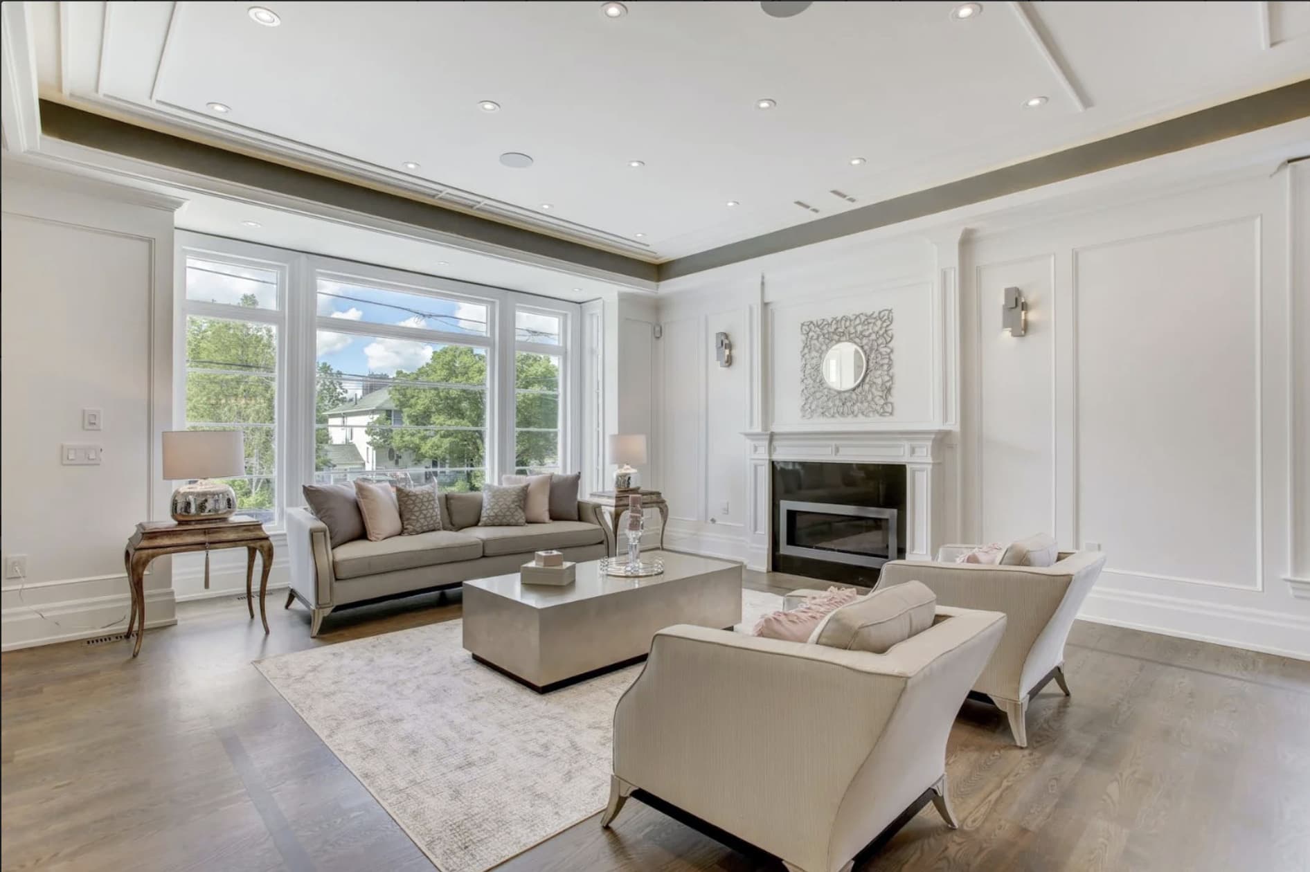 Living room with white wall panelling, a painted mantel and a tray ceiling
