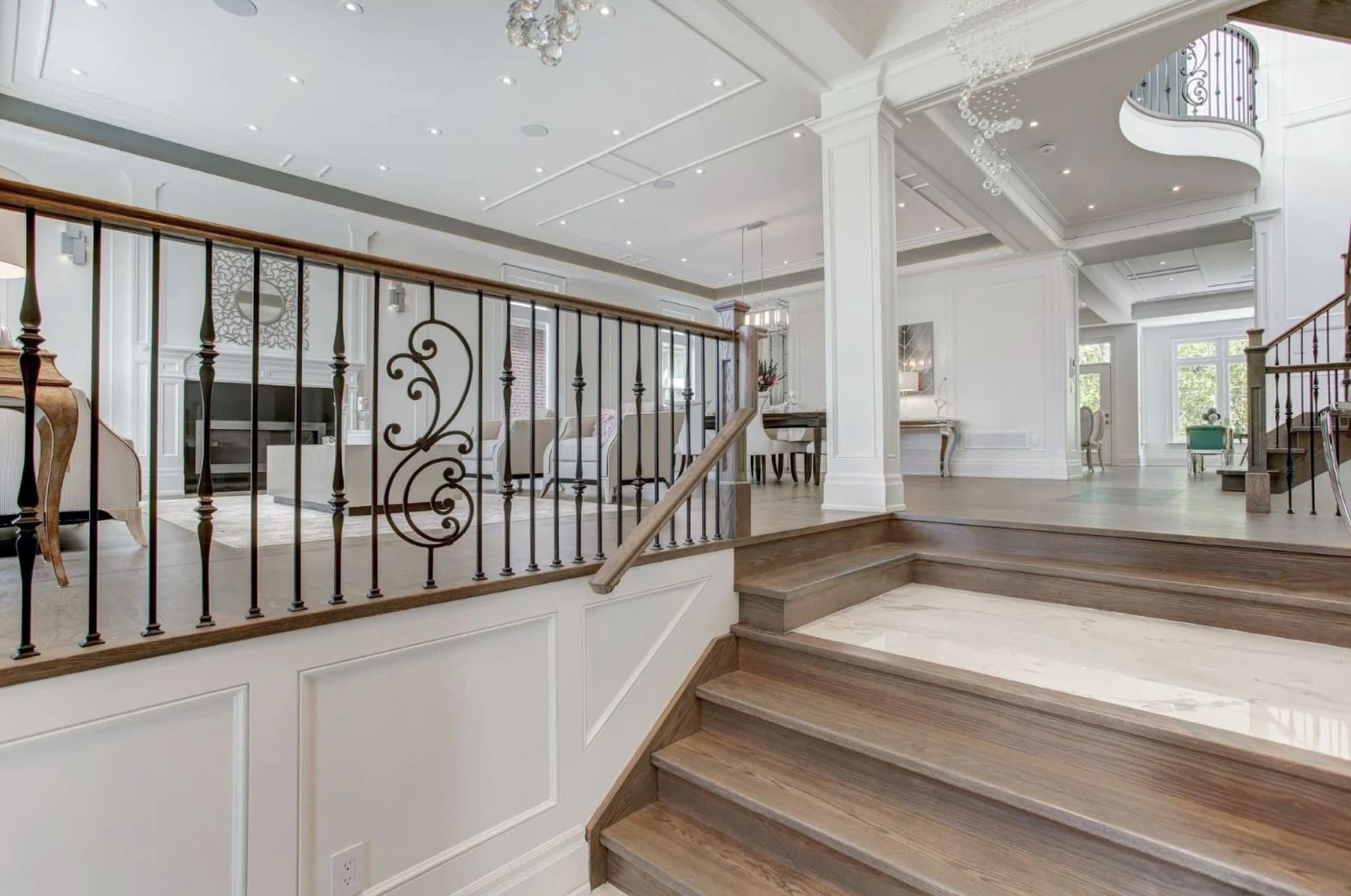 Stair landing with a wrought iron railing, panelled half wall and painted columns