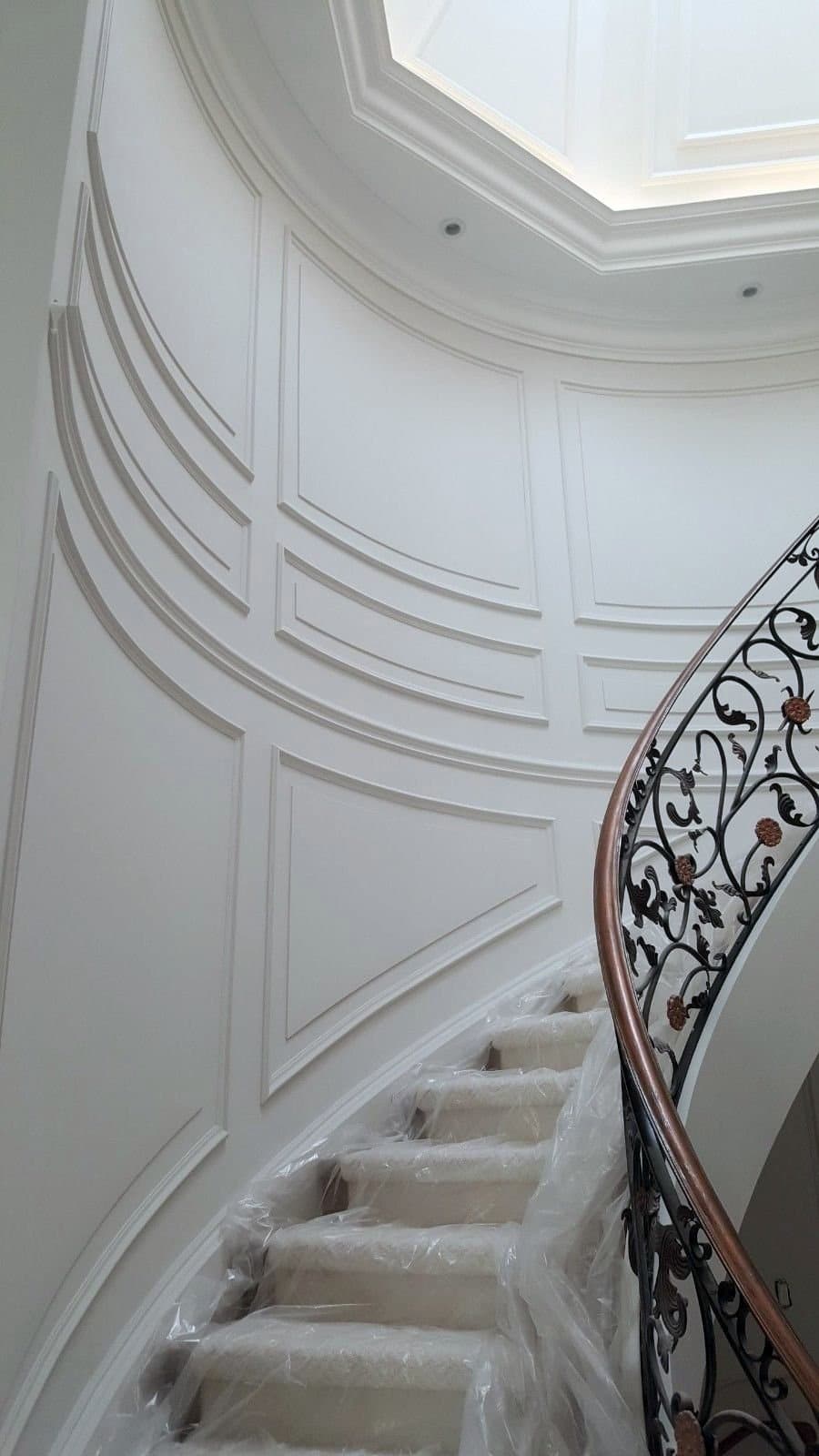 Curved stairwell wall with radiused panel mouldings following the round wall