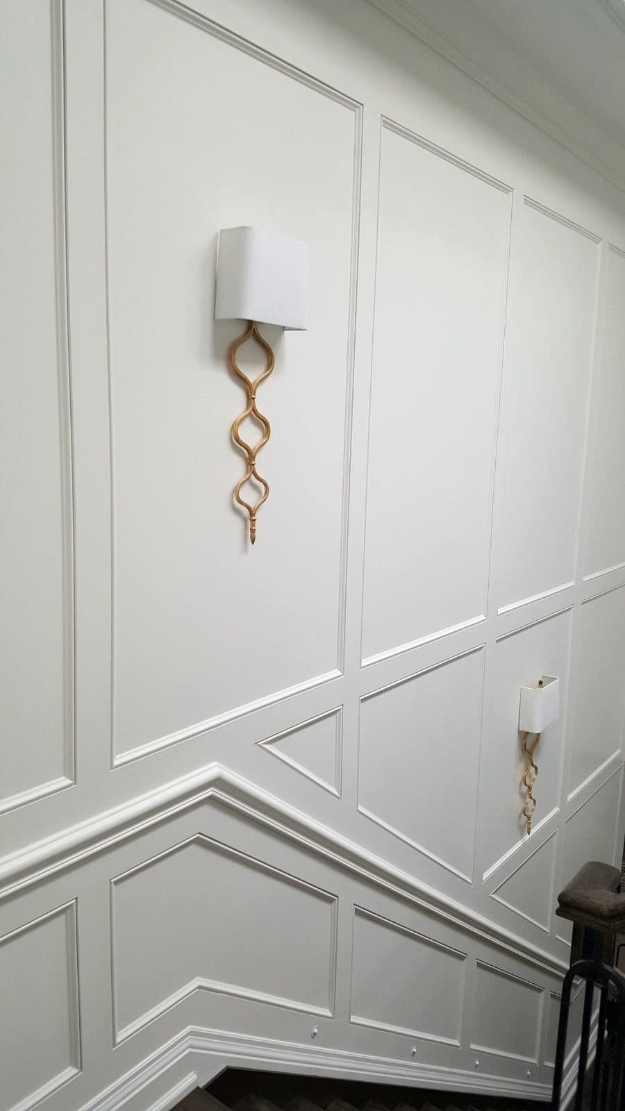 Stairwell wall panelling raked to follow the stair, with brass sconces