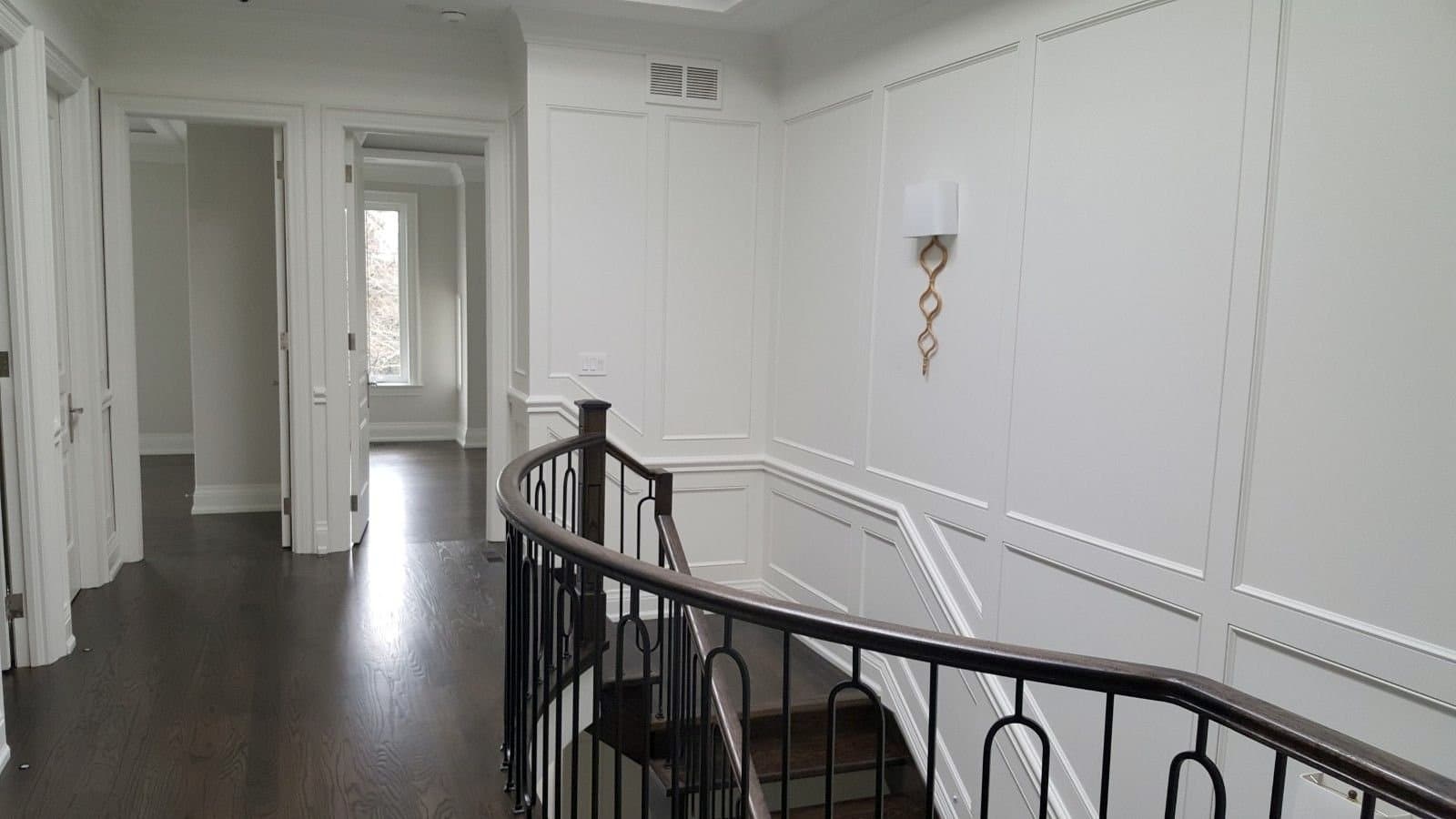 Upper hall with panelled walls and a curved iron railing over the stairwell