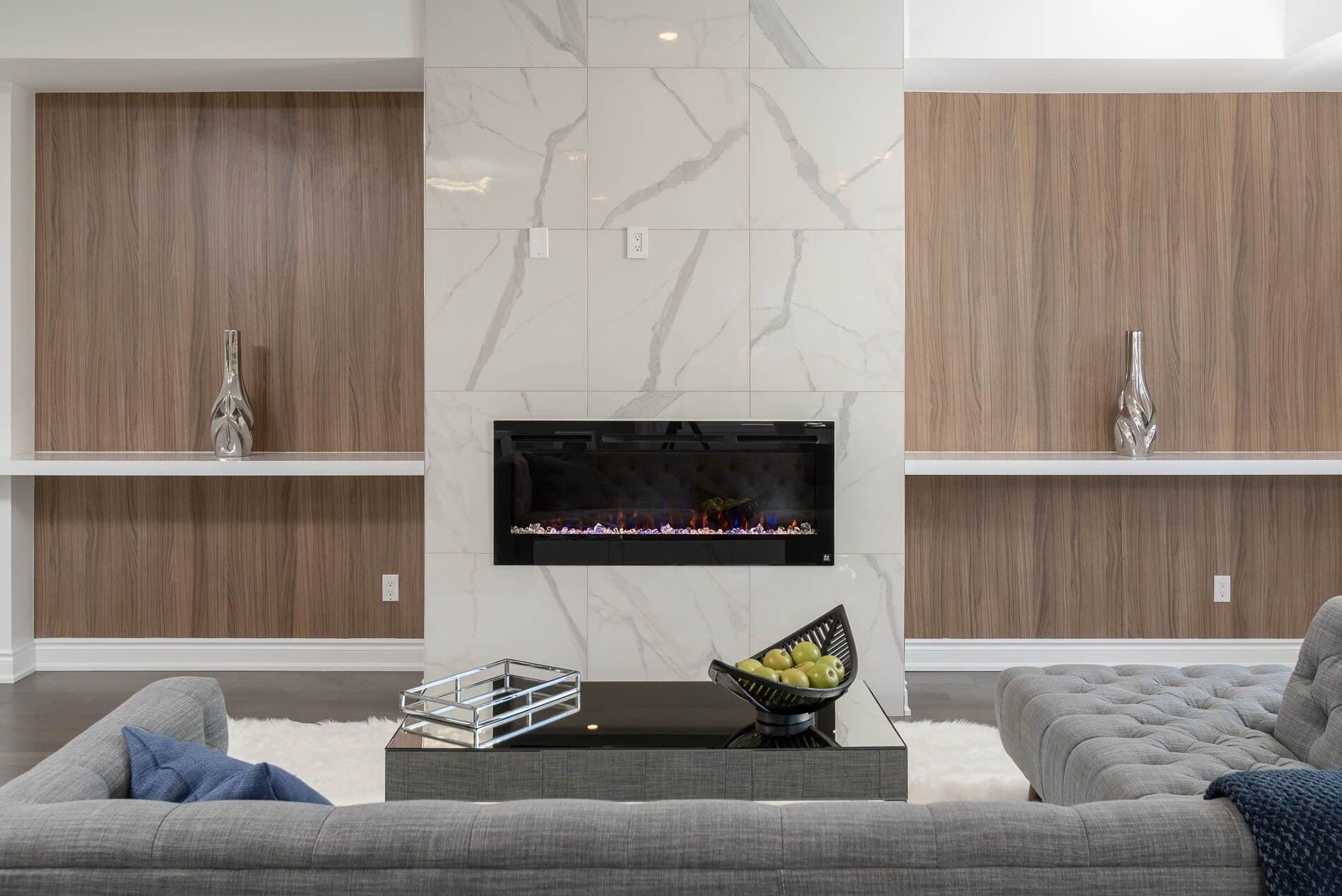 Walnut wall panels flanking a marble fireplace with floating shelves