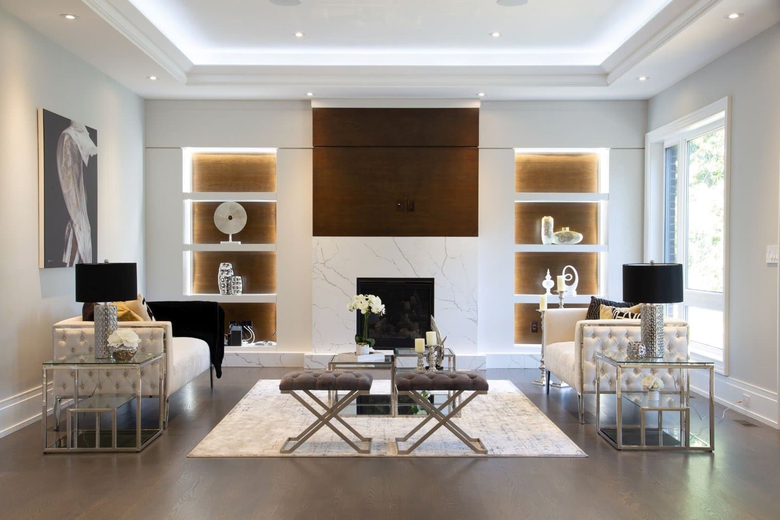Living room wall unit with backlit walnut niches beside a marble fireplace