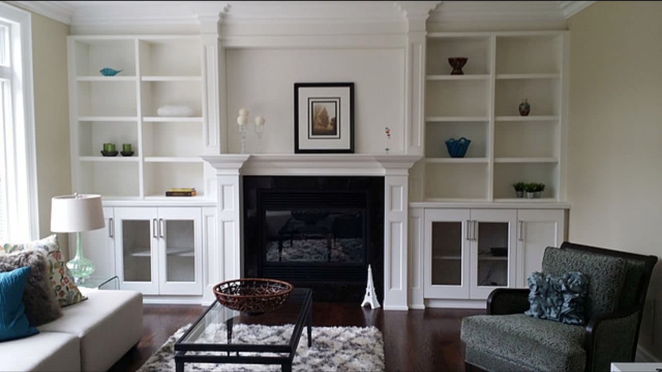 White built in bookcases and cabinets framing a fireplace surround