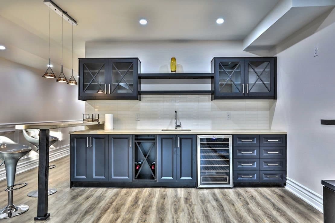 Navy wet bar cabinetry with glazed upper doors, wine rack and wine fridge