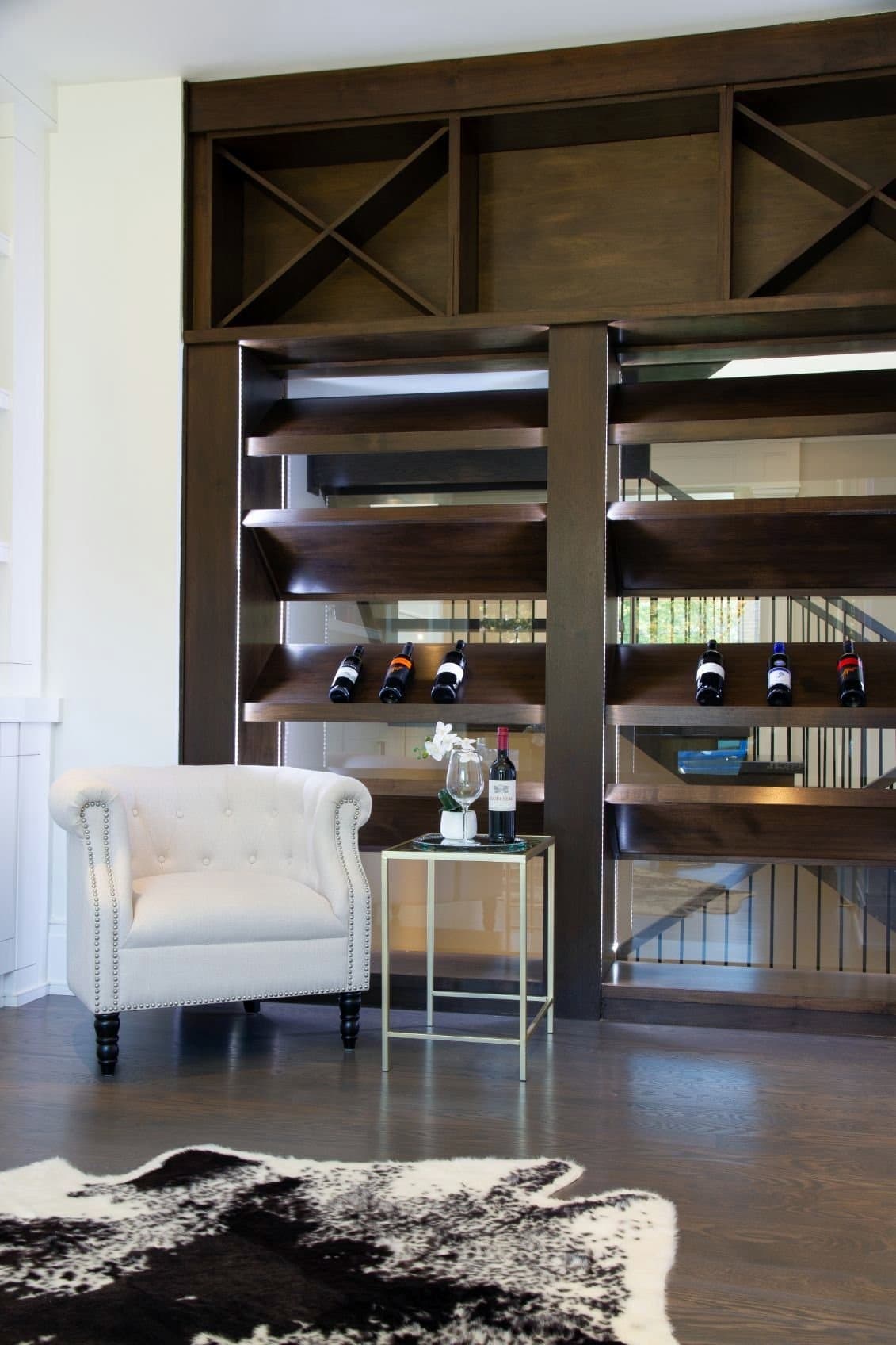 Dark walnut wine rack and open shelving used as a divider above the stair