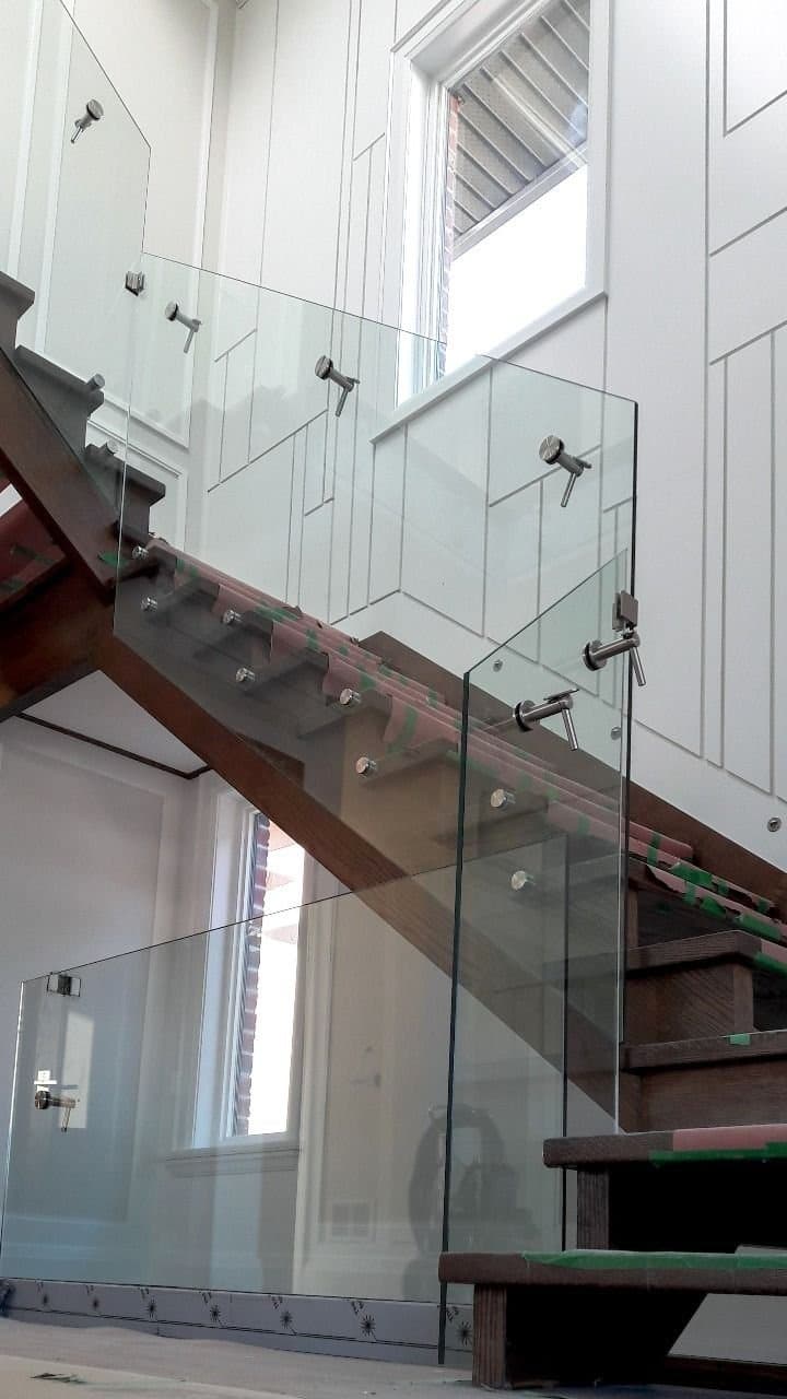 Glass stair railing being fitted to a stained oak stringer